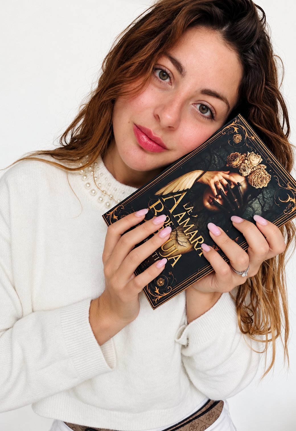 Alex Martino holding her novel Á de Ámara B de Bruja against her cheek